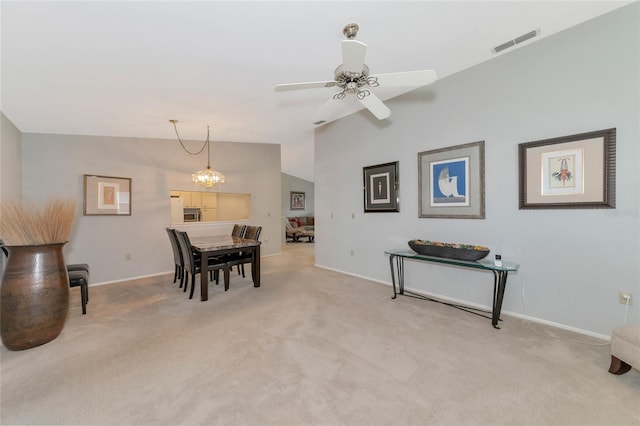 dining area with ceiling fan with notable chandelier, lofted ceiling, and light carpet