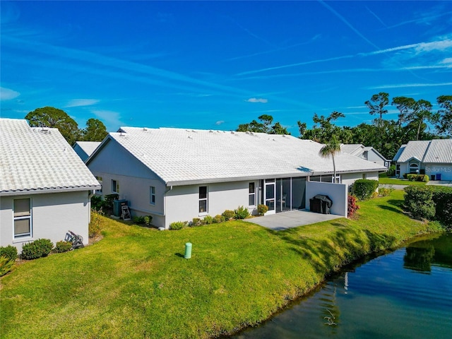 back of property featuring a yard, a water view, a patio area, and a sunroom