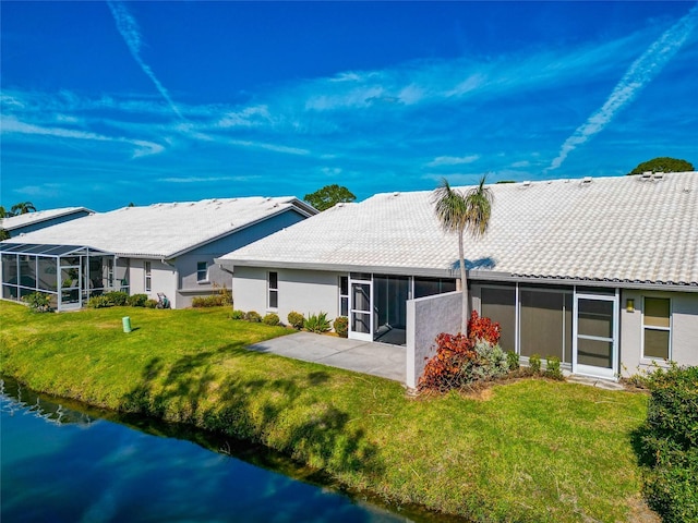 rear view of property featuring a lawn, a water view, and a patio