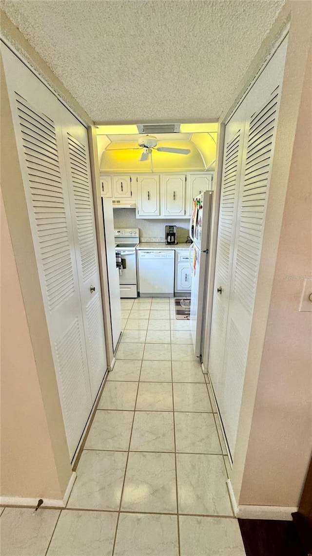 corridor featuring light tile patterned floors and a textured ceiling