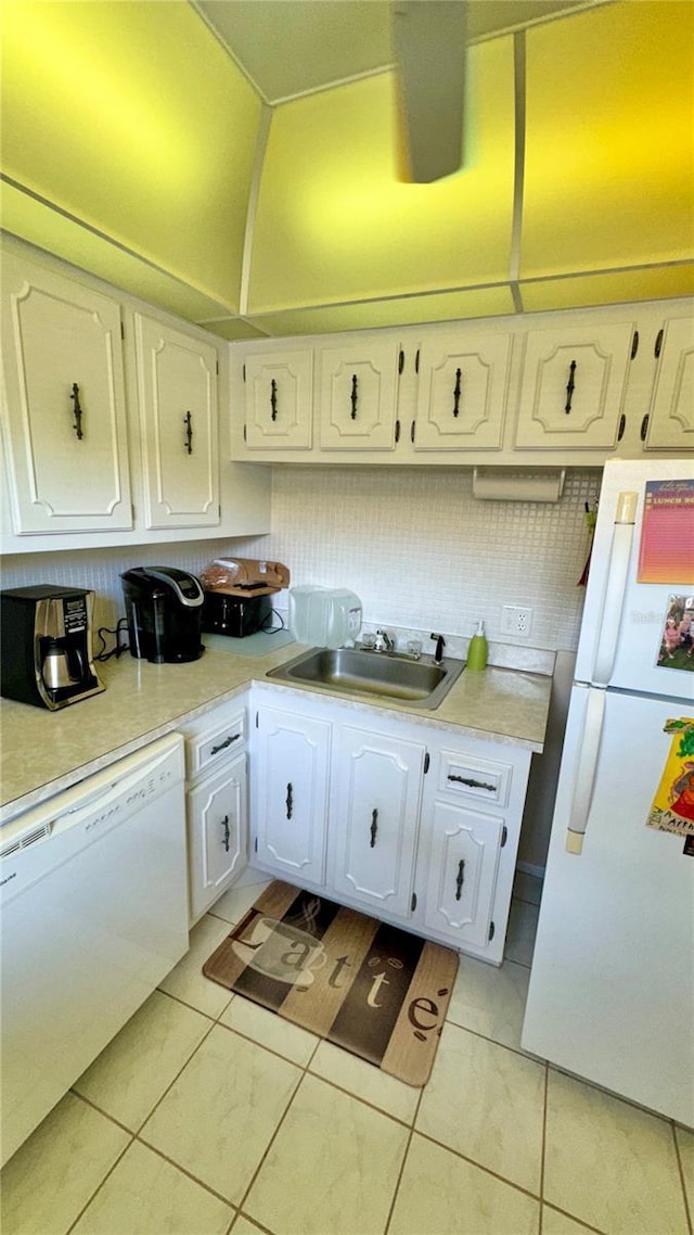 kitchen with tasteful backsplash, white appliances, sink, light tile patterned floors, and white cabinets