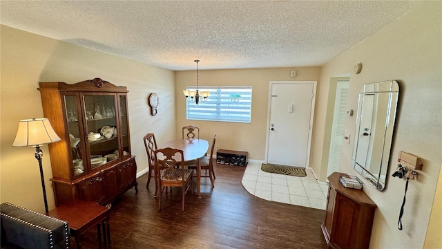 dining area with dark hardwood / wood-style flooring, a textured ceiling, and an inviting chandelier