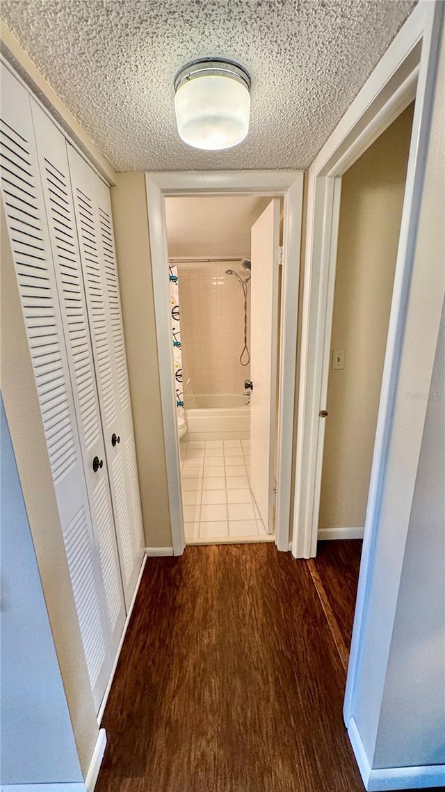 corridor featuring wood-type flooring and a textured ceiling