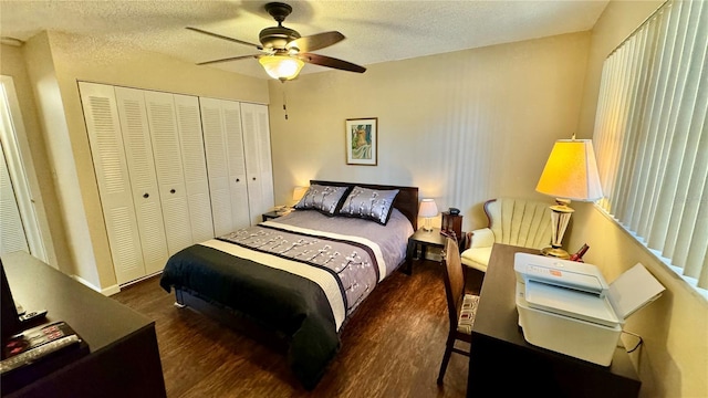 bedroom with a textured ceiling, ceiling fan, dark wood-type flooring, and a closet