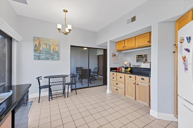 kitchen with decorative light fixtures, white refrigerator, light tile patterned flooring, and a chandelier