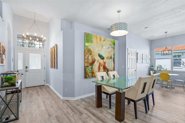 dining space featuring an inviting chandelier, a textured ceiling, and light wood-type flooring