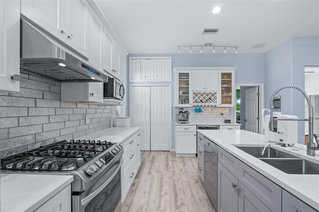 kitchen with stainless steel appliances, sink, white cabinets, and light stone counters