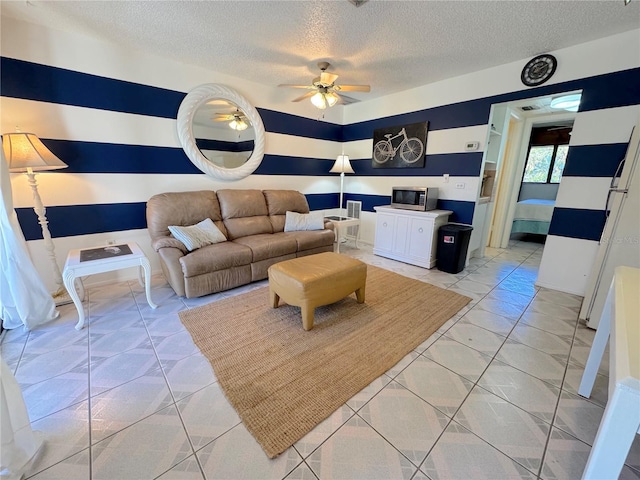 living room with ceiling fan and a textured ceiling