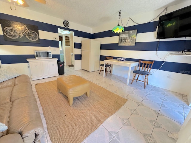 living room featuring ceiling fan, light tile patterned floors, and a textured ceiling