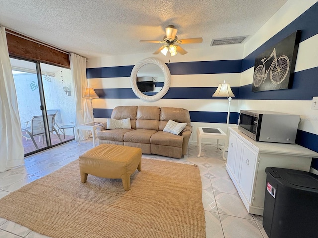 living room with light tile patterned floors, a textured ceiling, and ceiling fan