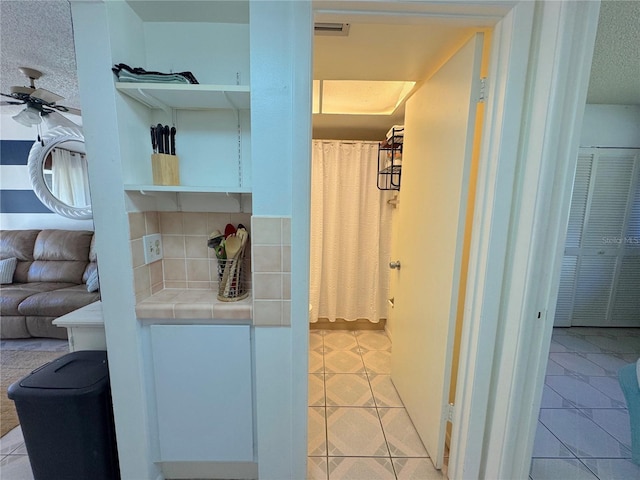 bathroom with decorative backsplash, a textured ceiling, tile patterned floors, and ceiling fan