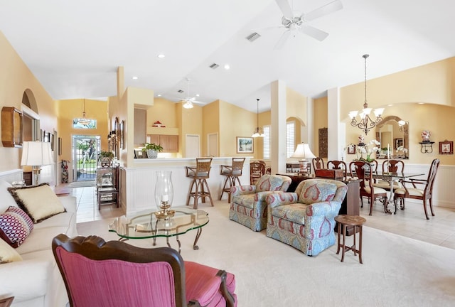 living room with ceiling fan with notable chandelier, light tile patterned flooring, and a high ceiling