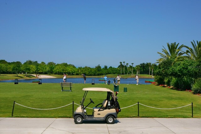 surrounding community with a water view and a lawn