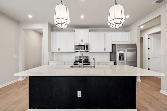 kitchen with hanging light fixtures, a center island with sink, stainless steel appliances, and sink