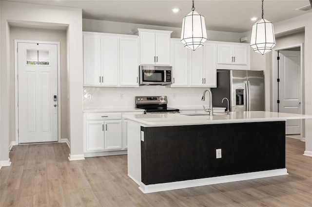 kitchen featuring a center island with sink, stainless steel appliances, decorative light fixtures, and sink