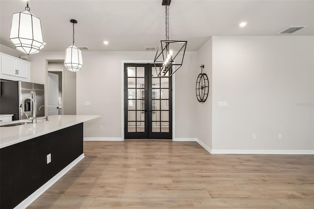 kitchen with french doors, sink, stainless steel fridge, decorative light fixtures, and light wood-type flooring