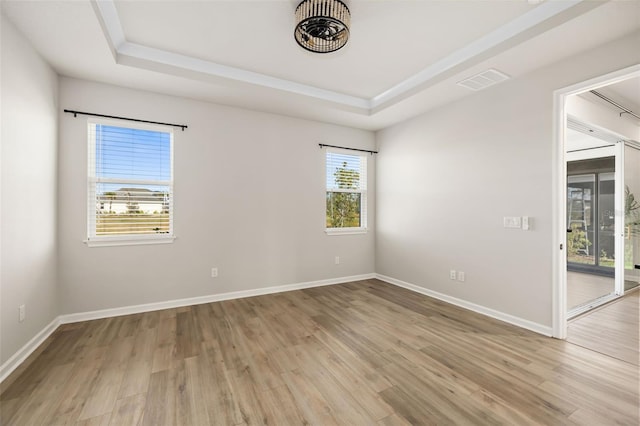 unfurnished room with a raised ceiling and light wood-type flooring