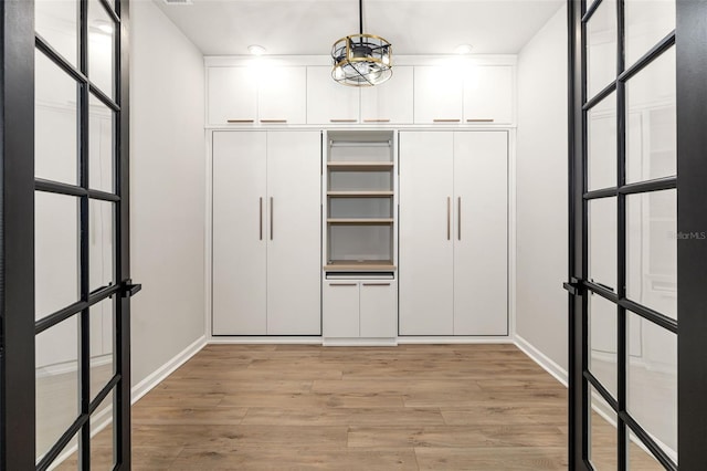 walk in closet with light wood-type flooring and a chandelier