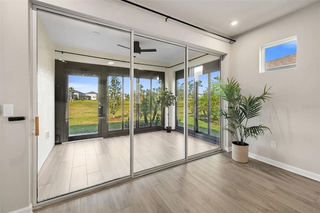 doorway with hardwood / wood-style floors, ceiling fan, and a healthy amount of sunlight