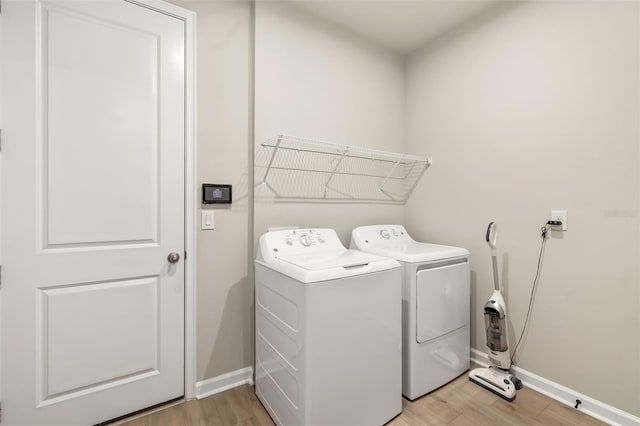 laundry area with independent washer and dryer and light wood-type flooring