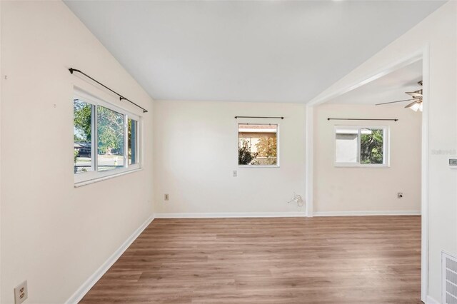 unfurnished room featuring plenty of natural light, vaulted ceiling, ceiling fan, and light hardwood / wood-style flooring