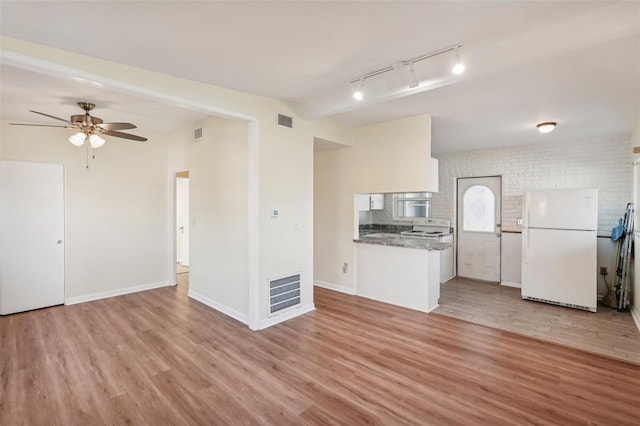 kitchen with white cabinets, white appliances, brick wall, and light hardwood / wood-style flooring