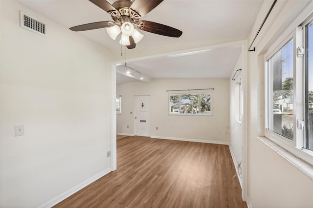 empty room with ceiling fan, vaulted ceiling, and hardwood / wood-style flooring