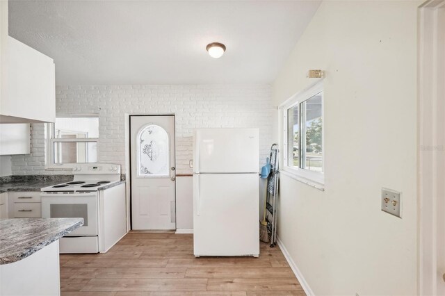 kitchen with white appliances, light hardwood / wood-style floors, white cabinetry, and brick wall