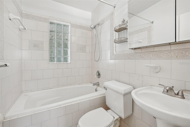 full bathroom with sink, tiled shower / bath, tile walls, and toilet