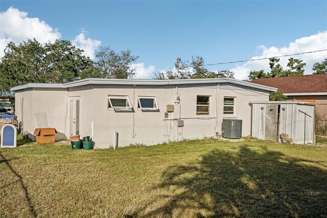 rear view of house with central AC and a lawn