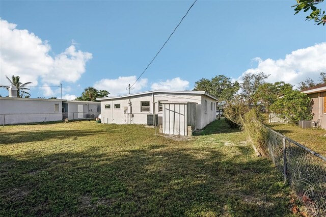 rear view of property with a lawn and cooling unit