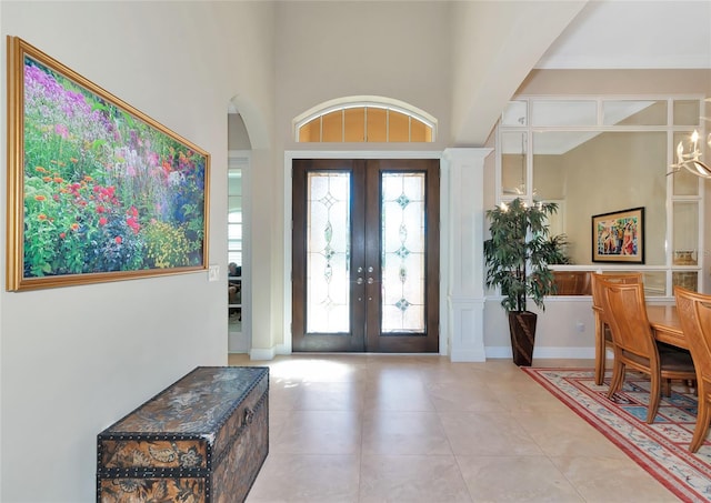 foyer entrance with a notable chandelier, a towering ceiling, and french doors