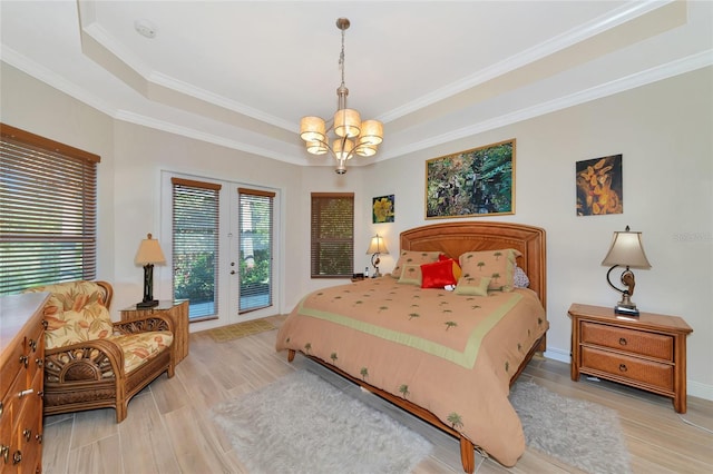 bedroom with access to exterior, an inviting chandelier, crown molding, light hardwood / wood-style floors, and a tray ceiling