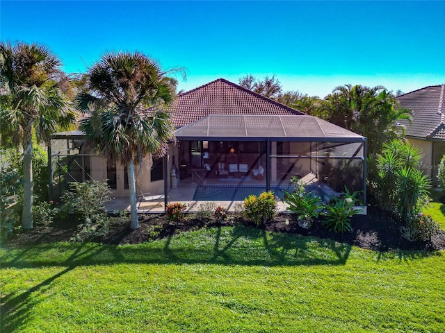 back of house with a lawn, glass enclosure, and a patio