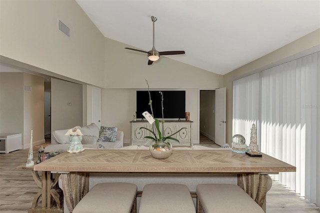 kitchen with a breakfast bar area, ceiling fan, light hardwood / wood-style flooring, and vaulted ceiling