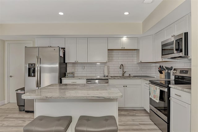 kitchen featuring white cabinetry, sink, stainless steel appliances, and light wood-type flooring