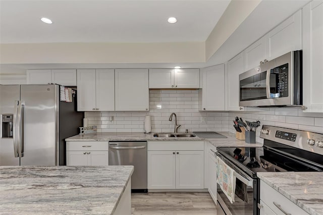 kitchen featuring light stone countertops, white cabinetry, sink, and stainless steel appliances