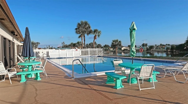 view of swimming pool featuring a water view and a patio