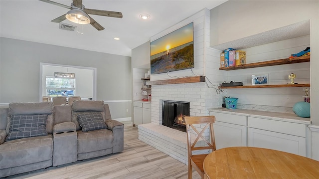 living room featuring ceiling fan, a fireplace, and light wood-type flooring