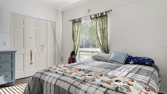 bedroom featuring hardwood / wood-style floors, ornamental molding, and a closet