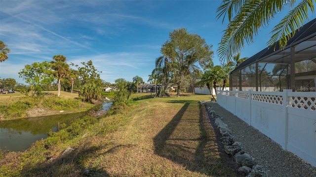 view of yard featuring glass enclosure and a water view