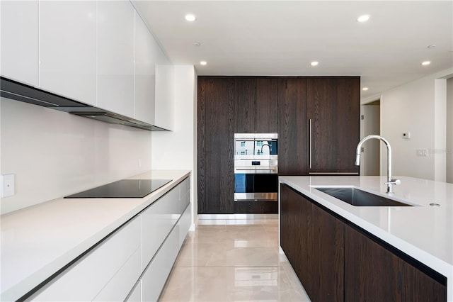 kitchen featuring dark brown cabinets, black electric cooktop, white cabinetry, and sink