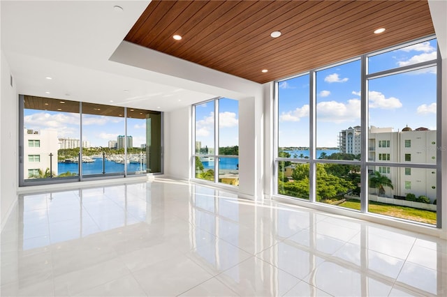 unfurnished room featuring floor to ceiling windows, a water view, light tile patterned floors, and a wealth of natural light