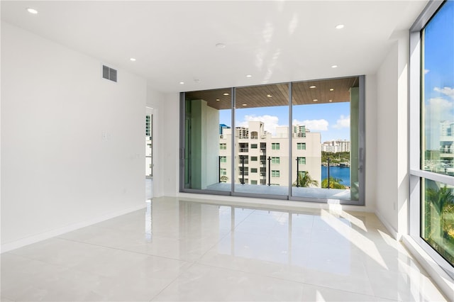 empty room with a water view, expansive windows, and light tile patterned flooring