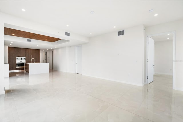 spare room featuring a tray ceiling and sink