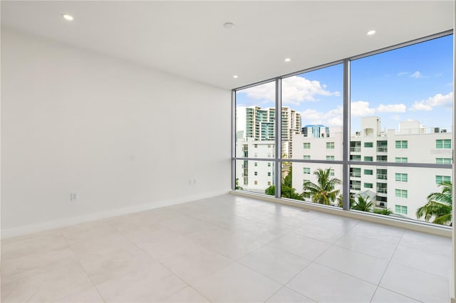 spare room featuring expansive windows and light tile patterned floors