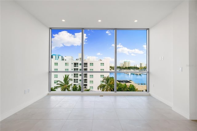 tiled empty room featuring expansive windows and a water view