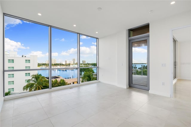 tiled empty room featuring floor to ceiling windows and a water view