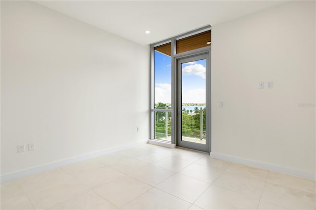 spare room featuring floor to ceiling windows and light tile patterned floors