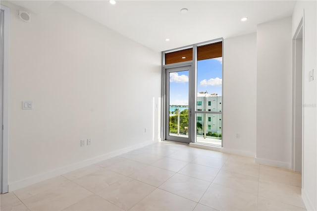 spare room featuring floor to ceiling windows and light tile patterned flooring